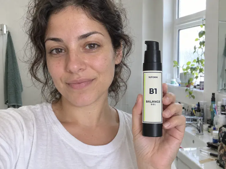 Maya holding the B1 Balance Gel bottle in her bathroom