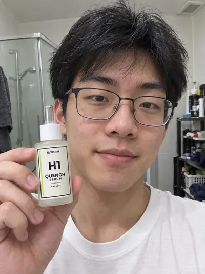 A man holding the H1 Quench Serum bottle in a bathroom